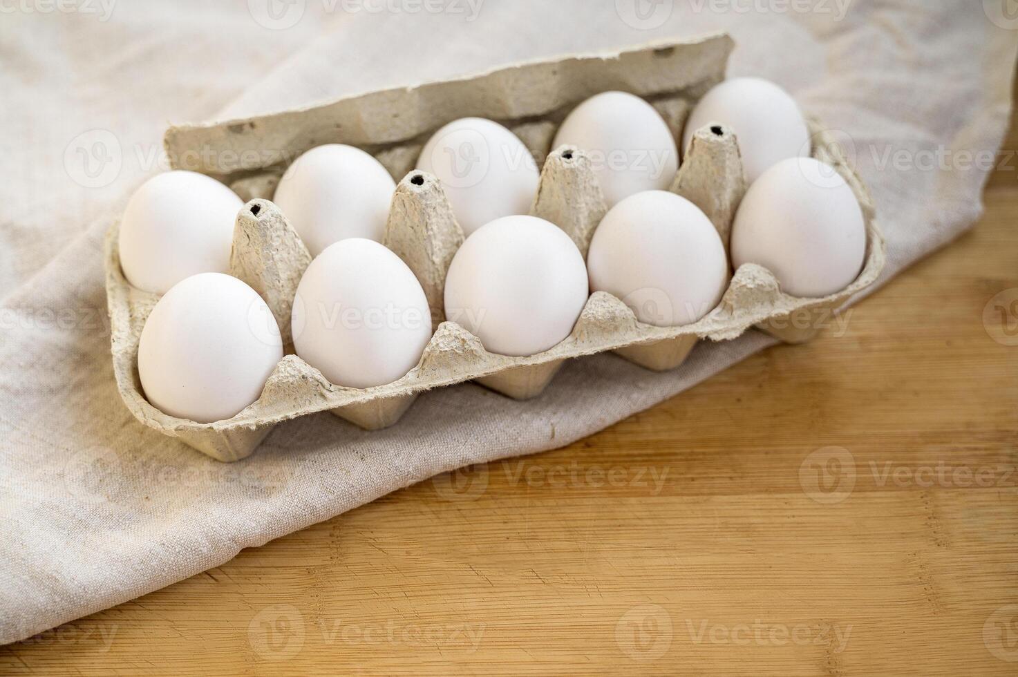 A chicken egg in a box. Meal. Easter. Black background. High quality photo. egg carton on wooden table with linen tablecloth. eggs are white photo