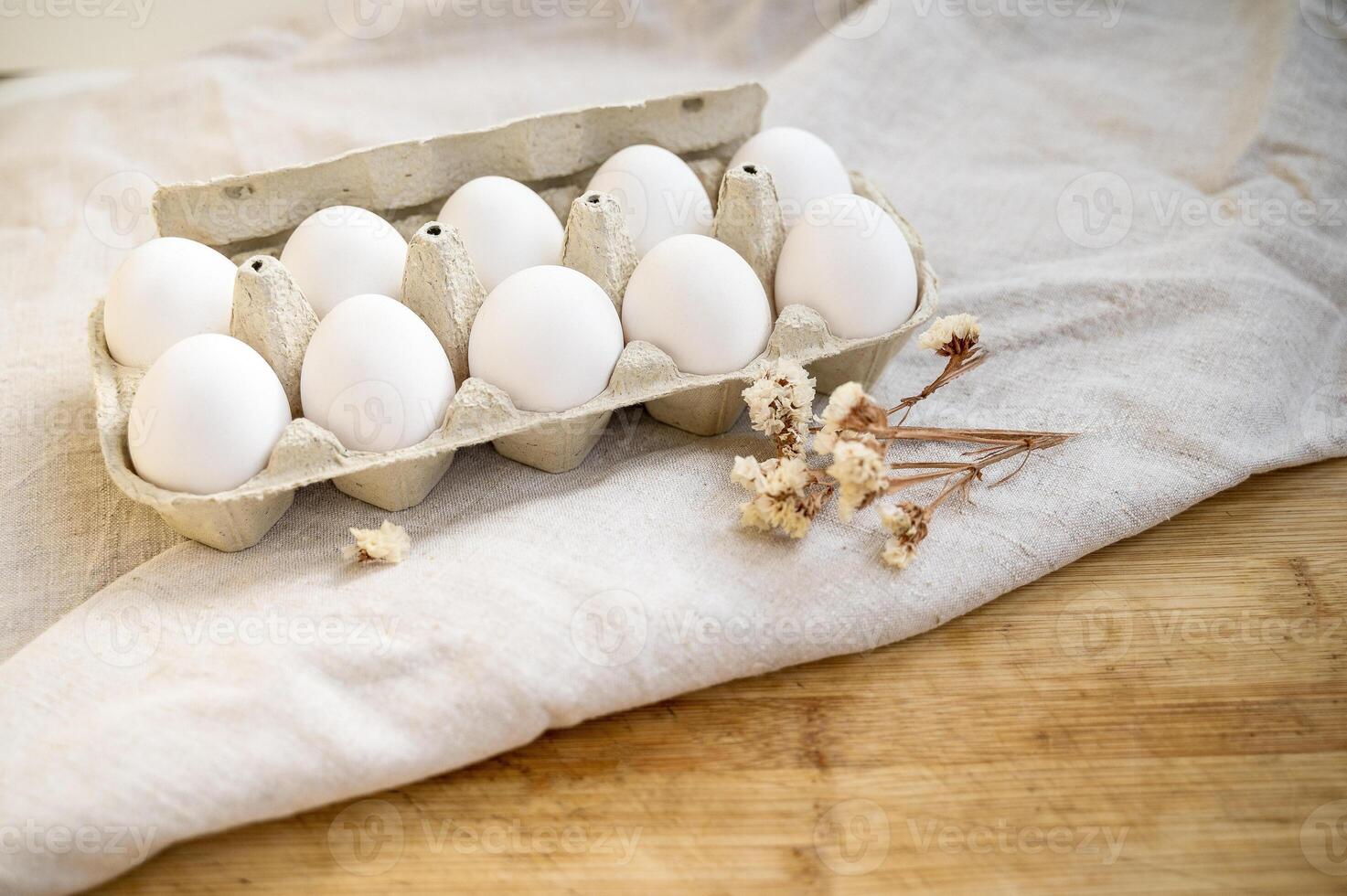 white eggs in a cardboard box, 10 pieces, on a surface made of natural materials.. A chicken egg in a box. Meal. Easter. egg carton on wooden table with linen tablecloth. photo