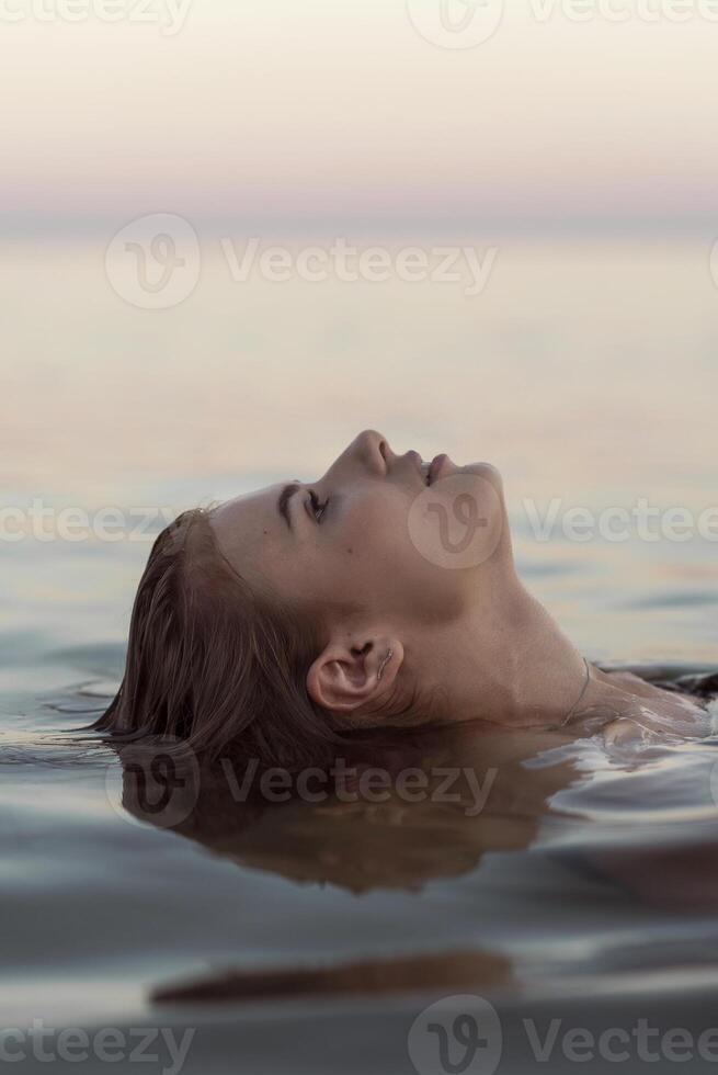beautiful girl is relaxing in the sea, relaxing and taking care of herself. Profile portrait of a young woman floating in water. High quality photo