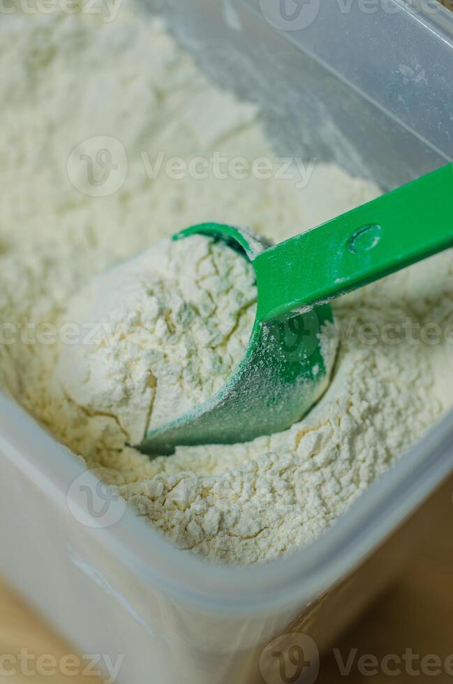 Flour in clear container with green scoop, food storage, kitchen detail. High quality photo