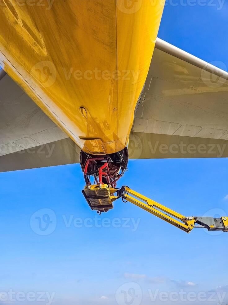 Aircraft maintenance work under the yellow fuselage with hydraulic lift. High quality photo