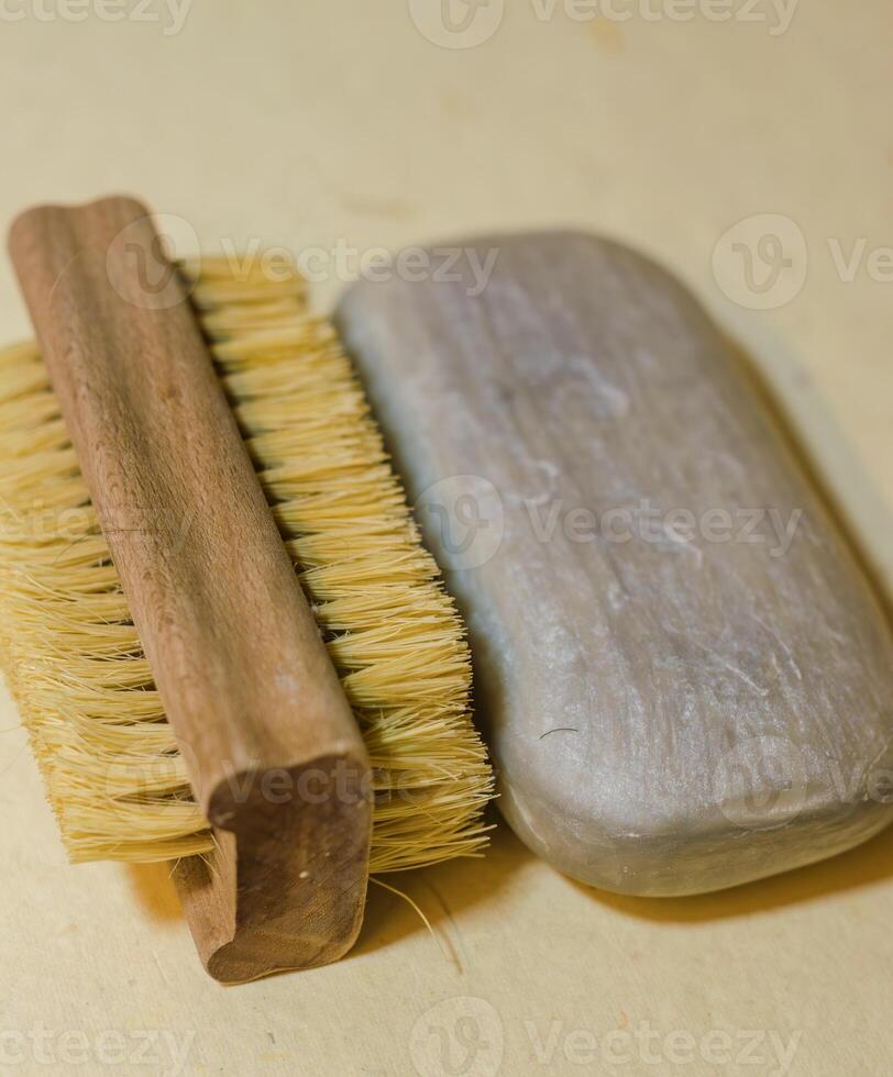 wooden boar bristle brush and smooth grey soap bar on warm beige surface. High quality photo