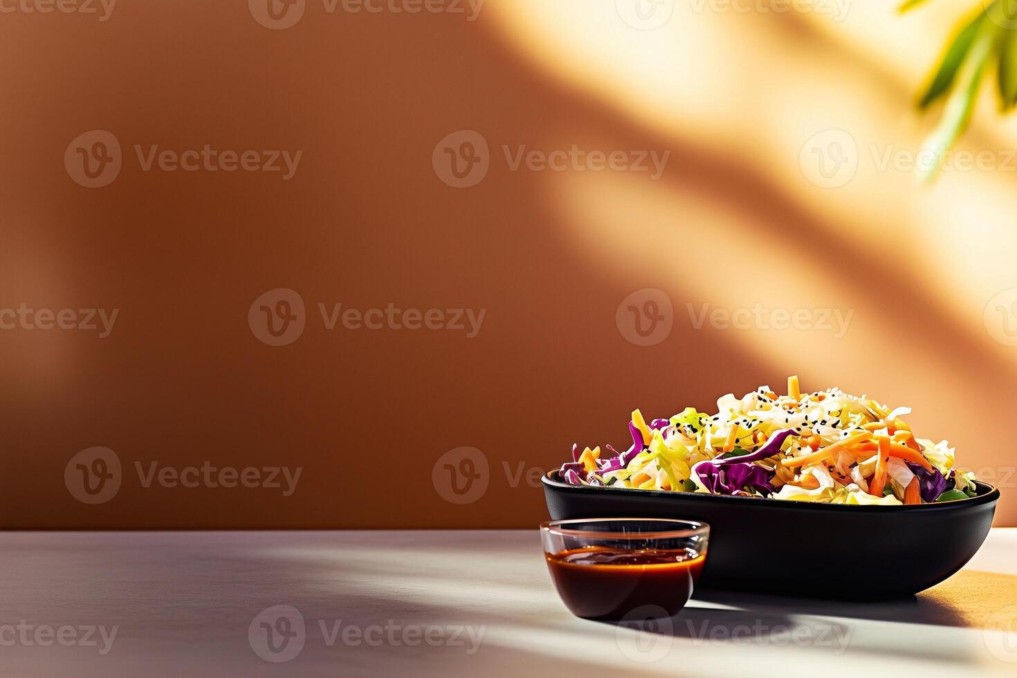 Fresh grab-and-go Asian salad with cabbage, carrots, sesame seeds, and teriyaki sauce in a black bowl, accompanied by a side of dressing. A vibrant and healthy meal option. . photo