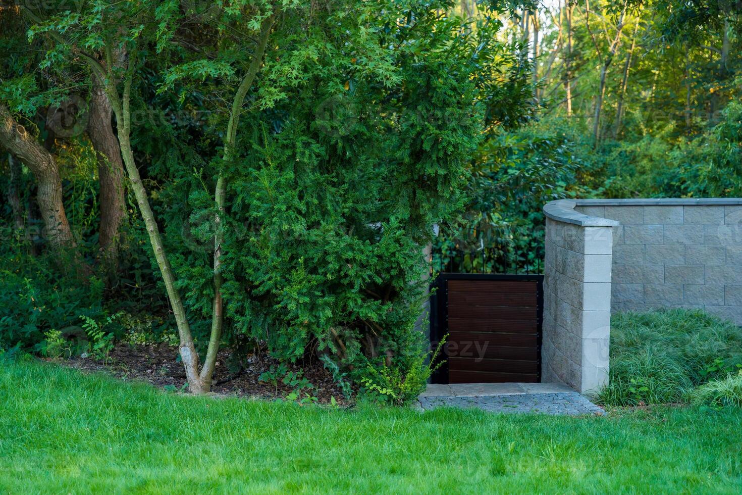 Lush garden gate surrounded by greenery and stone wall, calm atmosphere photo