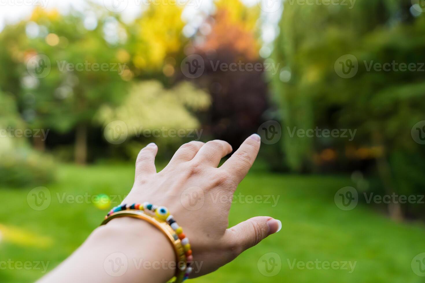 Outstretched hand reaching towards a blurred green garden on a sunny day photo