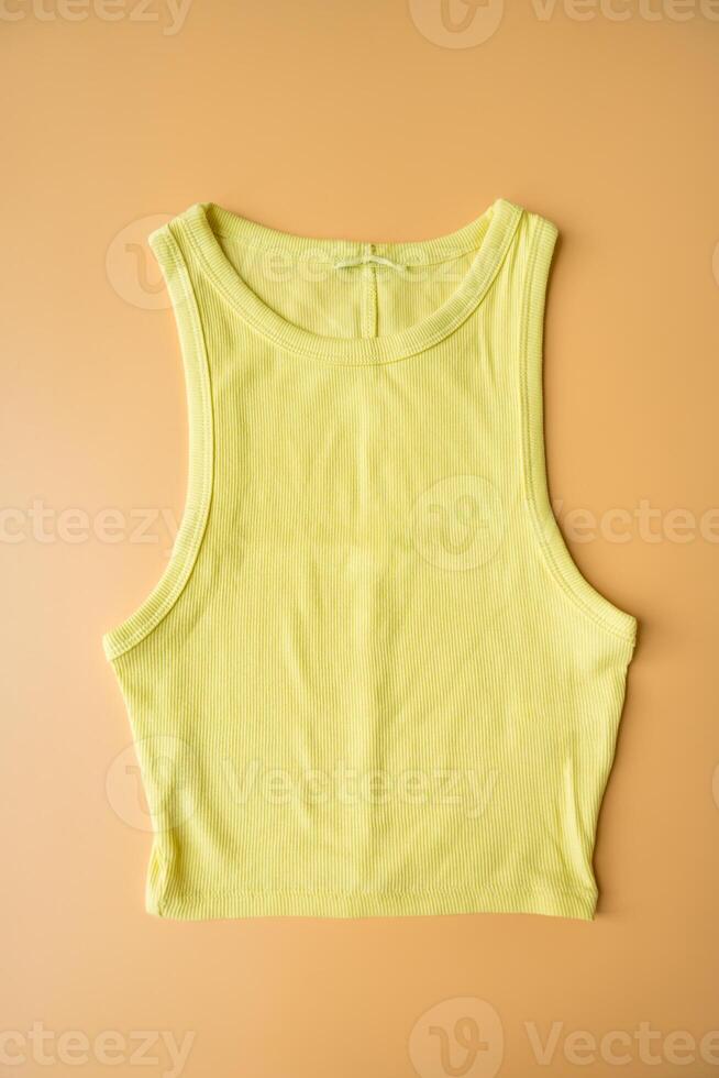 Lemon yellow cropped tank top on beige background, second-hand fashion and sustainable clothing photo