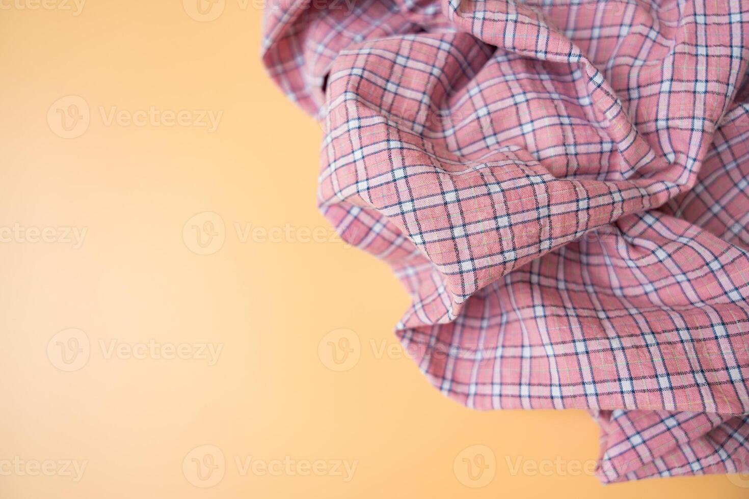 Pink plaid fabric with soft folds on beige background, textile material close-up, copy space. photo