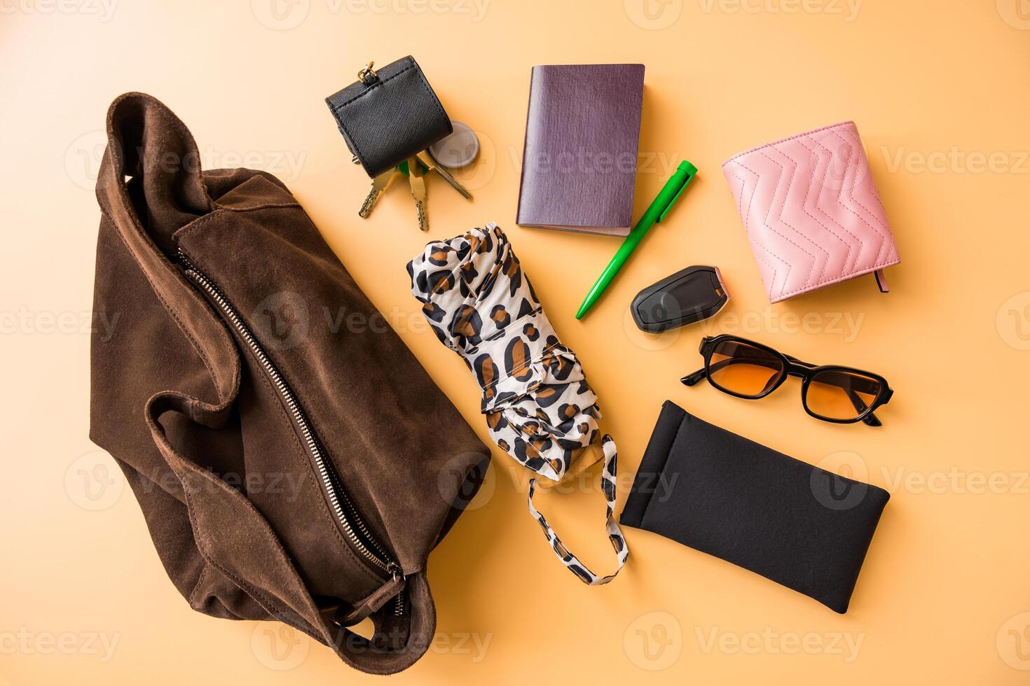 Flat lay of travel essentials with suede bag on pastel background photo
