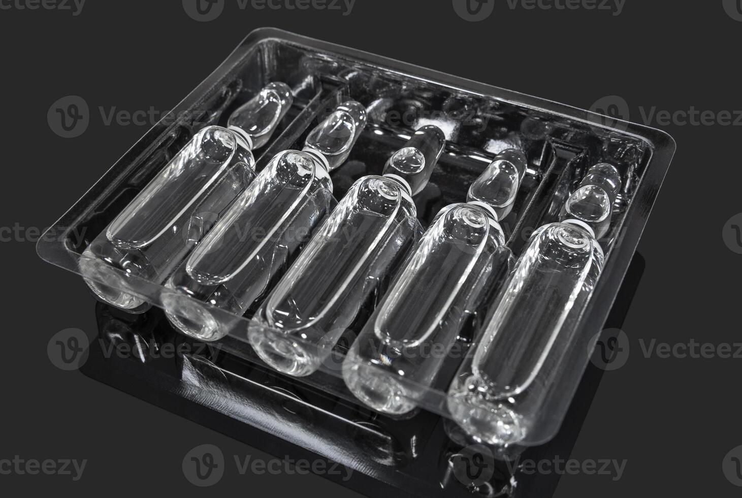 Ampoules with transparent medicine on a dark background photo
