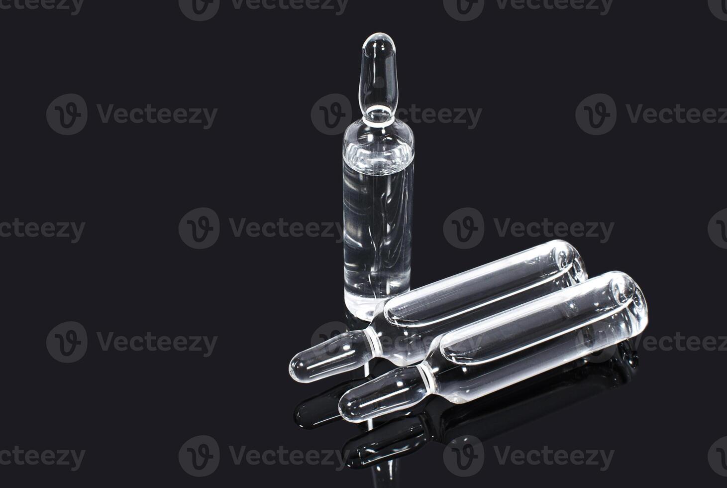 Ampules with transparent vaccine on dark background photo