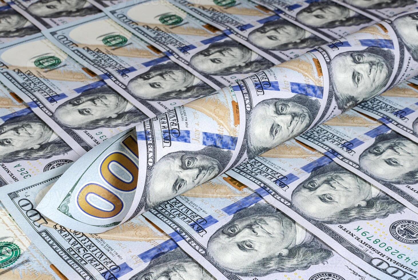 Twisted hundred dollar banknotes on the background of new dollar bills photo