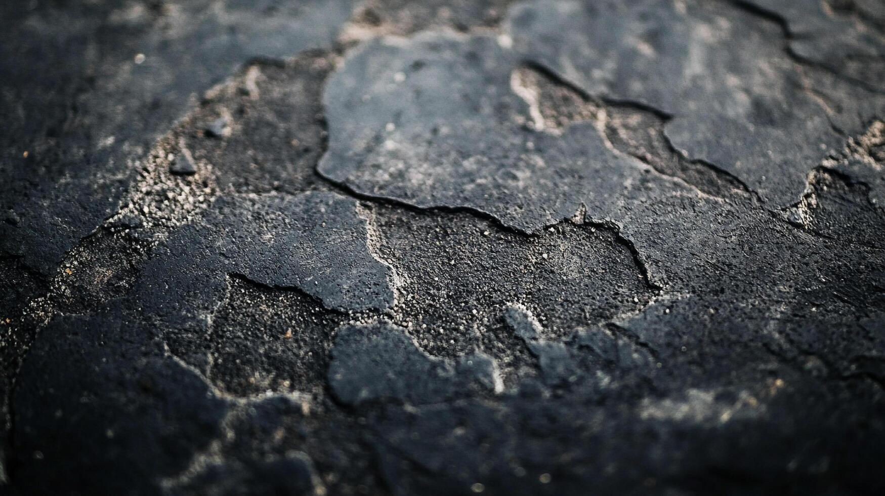 Close-up of cracked asphalt or weathered stone, showcasing texture and wear. Dramatic lighting enhances the surface details, creating a raw and organic look. photo