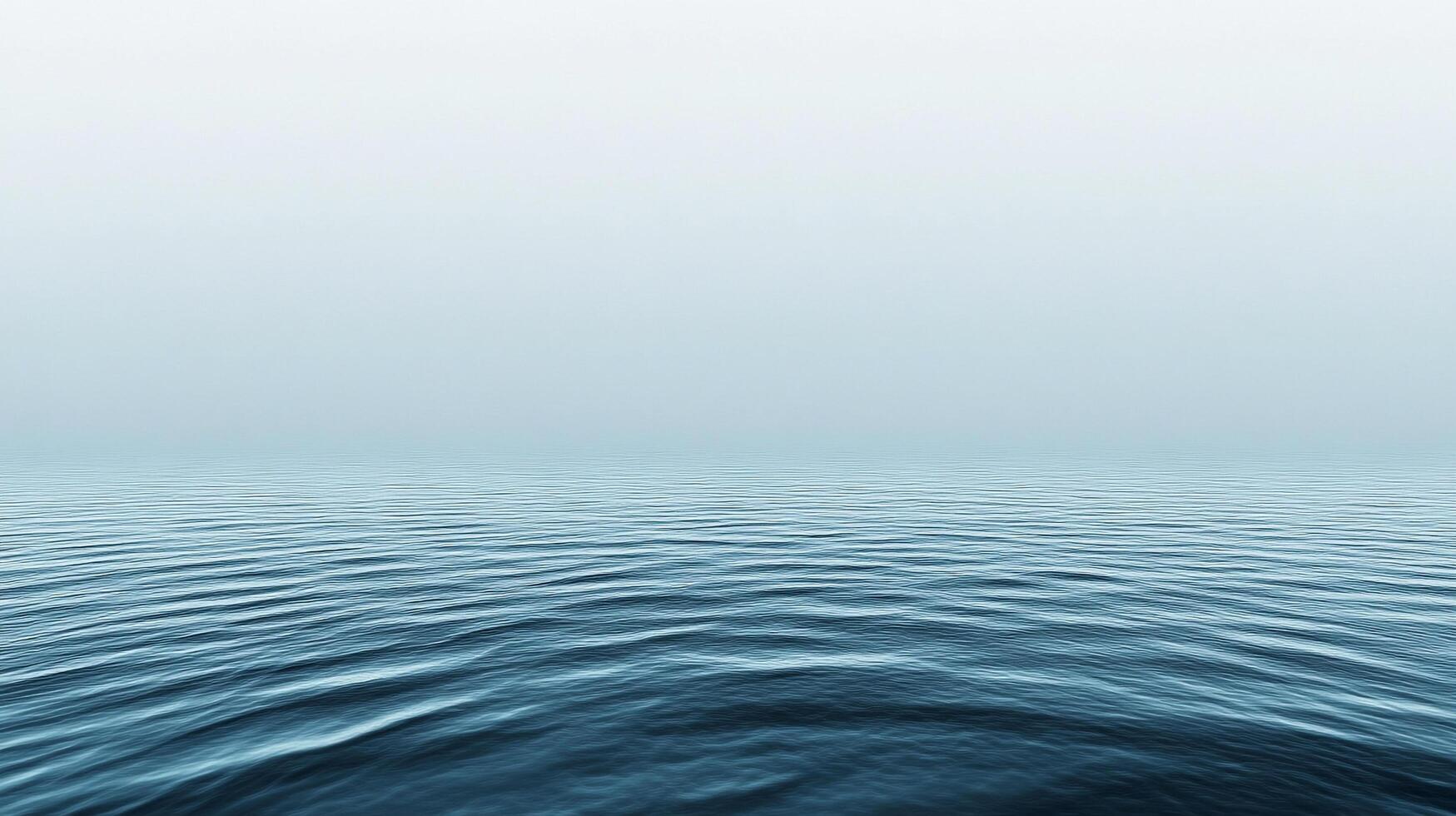 A serene, aquamarine expanse of the ocean, stretching to the horizon beneath a misty sky. The gentle waves create a tranquil seascape. photo