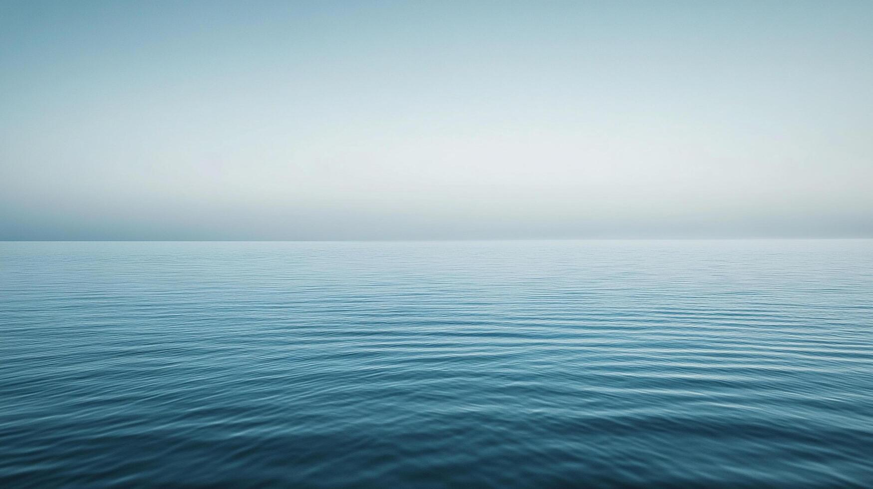 Serene water landscape with smooth, calming ripples on the ocean's surface under a tranquil, light blue sky. photo