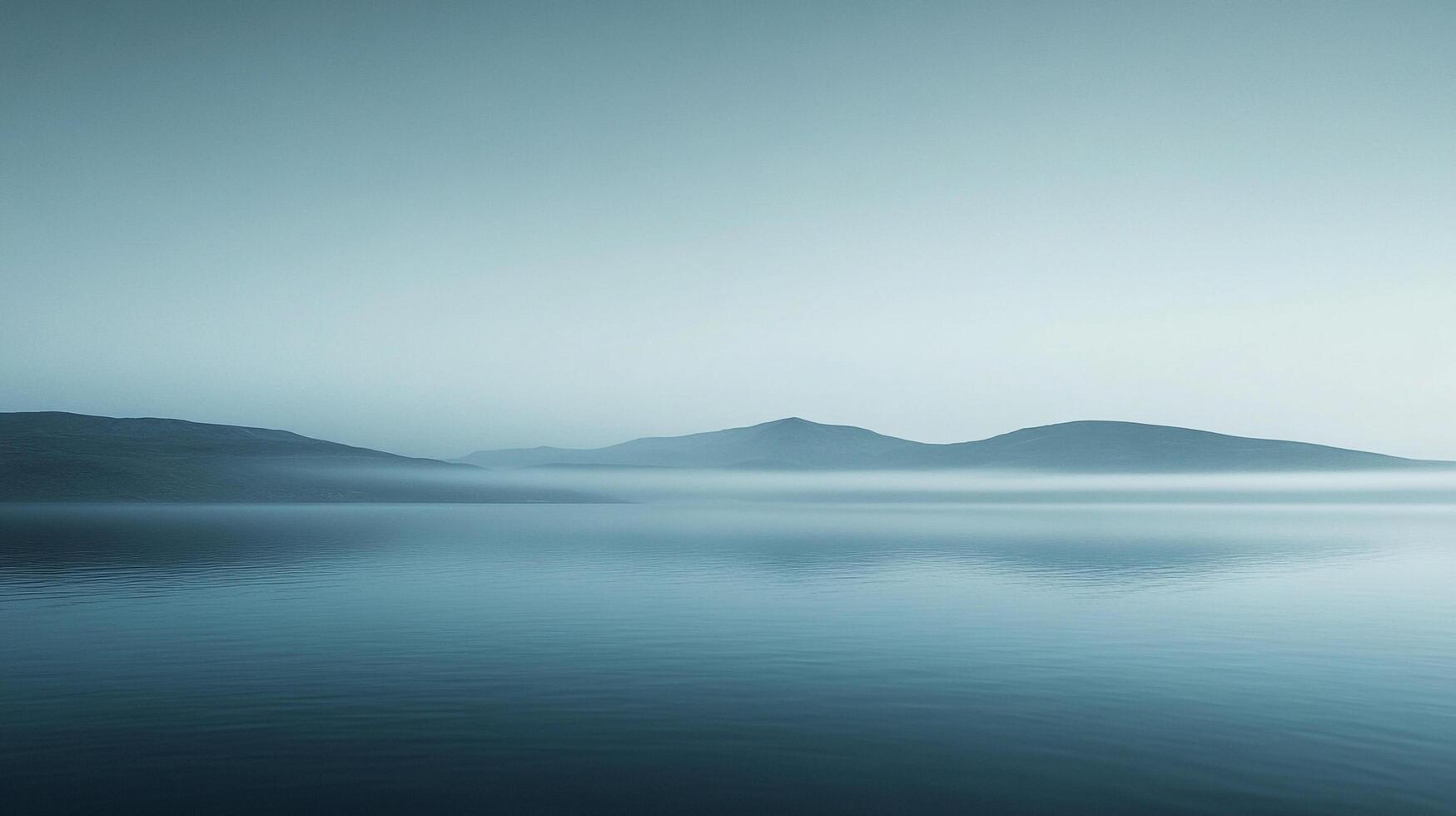 Serene vista of mist-shrouded mountains reflecting in calm lake waters under a pale sky, evoking tranquility and minimalist beauty. photo
