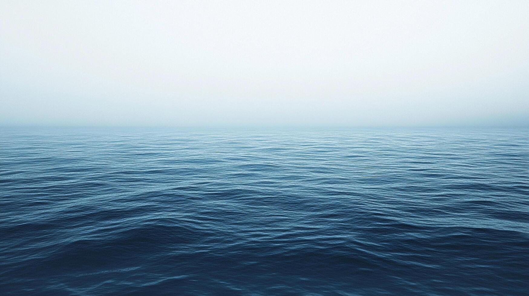 A tranquil ocean scene with gentle waves stretching to the horizon under a hazy, overcast sky, creating a peaceful, melancholic atmosphere. photo