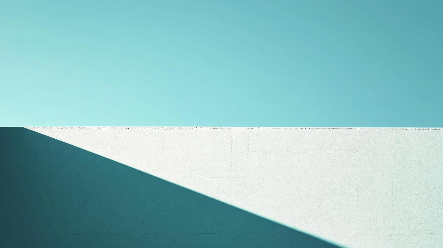 Minimalist composition of a white wall under a clear, bright blue sky, highlighting sharp lines and stark contrast with a deep shadow. photo