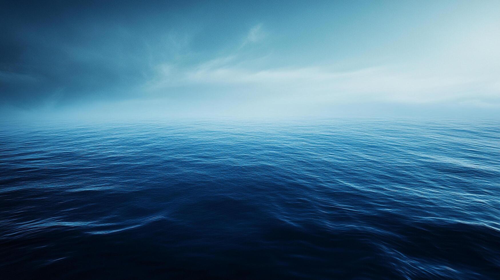 A serene expanse of ocean water stretches to the horizon, meeting a soft, cloudy sky. Tranquility in shades of blue. photo