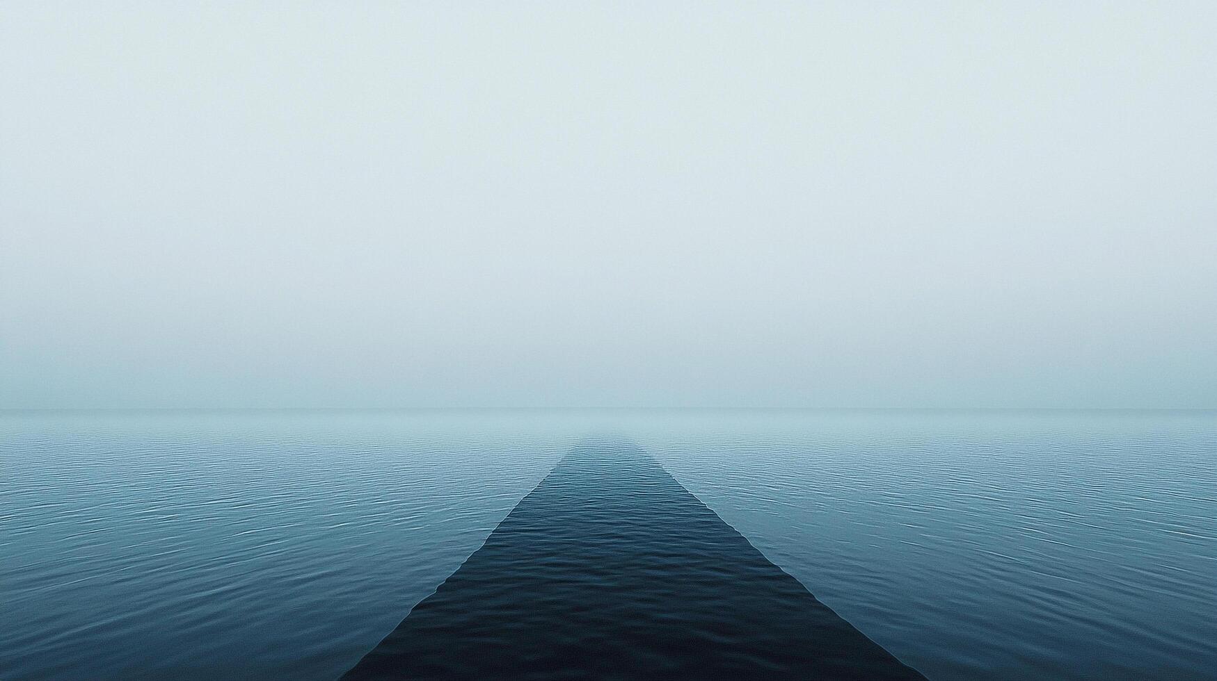 Serene ocean fading into a misty horizon, minimalist and calm, showcasing vastness and tranquility. The water surface is still and blue. photo