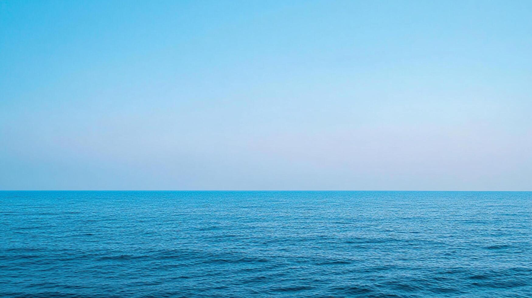 A tranquil seascape of a calm, rippling sea meeting a clear, expansive sky, evoking peace and vastness in its minimalist beauty. photo