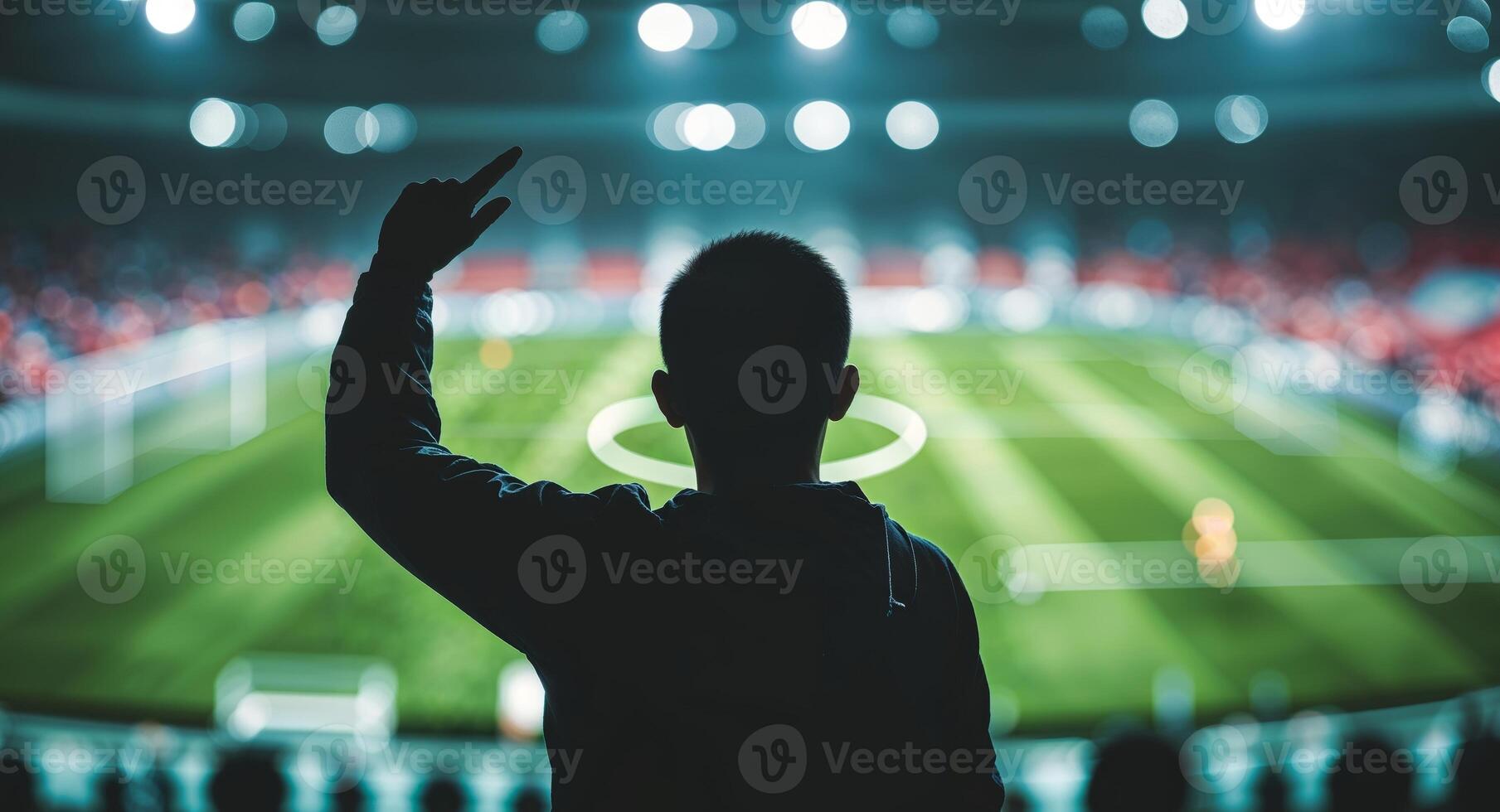A man is raising his hand in front of a soccer stadium photo