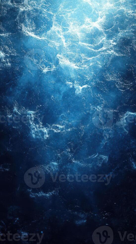 Turbulent ocean water illuminated by sunlight creates a captivating display of blue hues and frothy waves photo