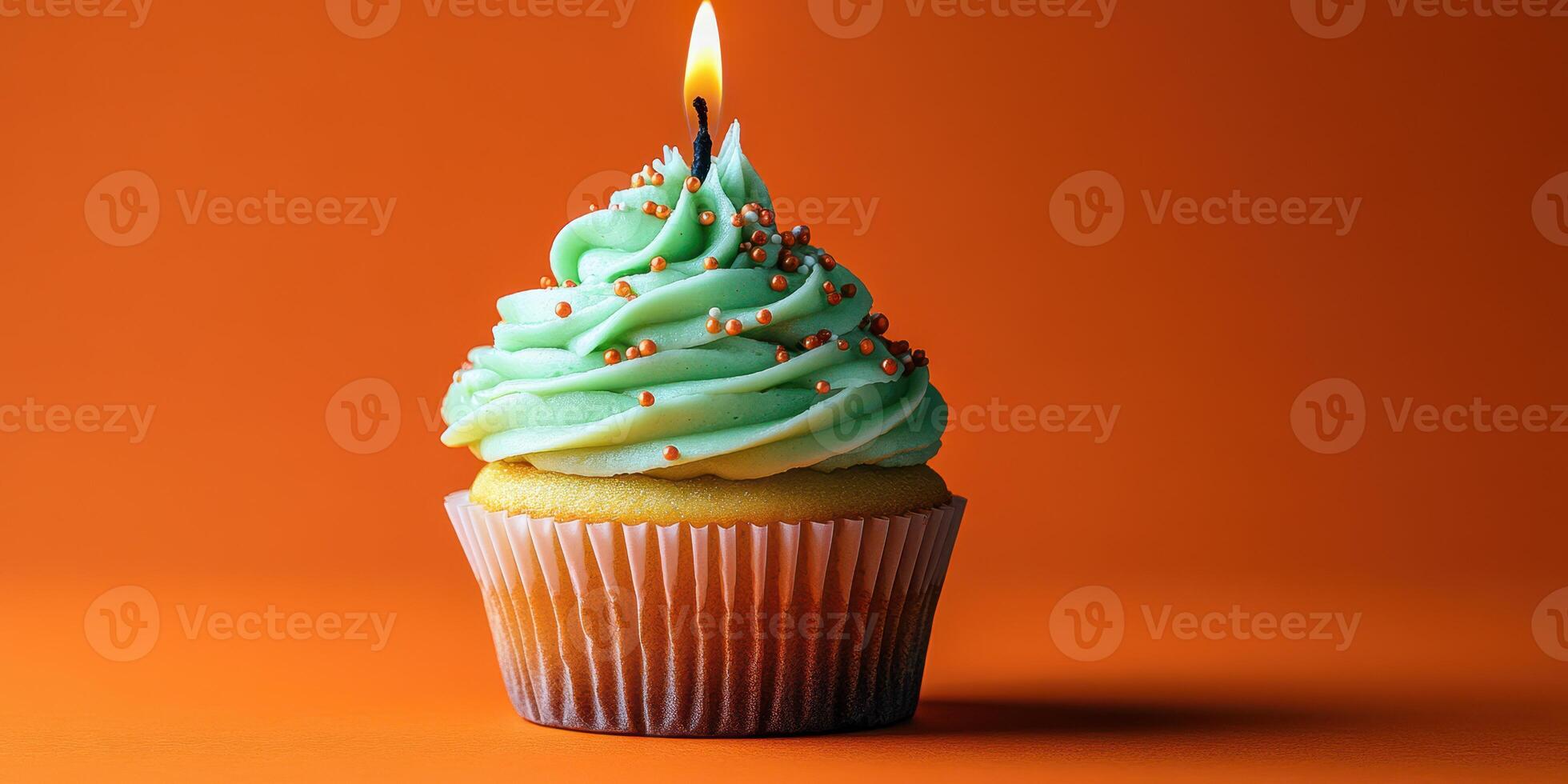 Colorful cupcake with mint frosting and a candle on a vibrant orange background during a celebration photo