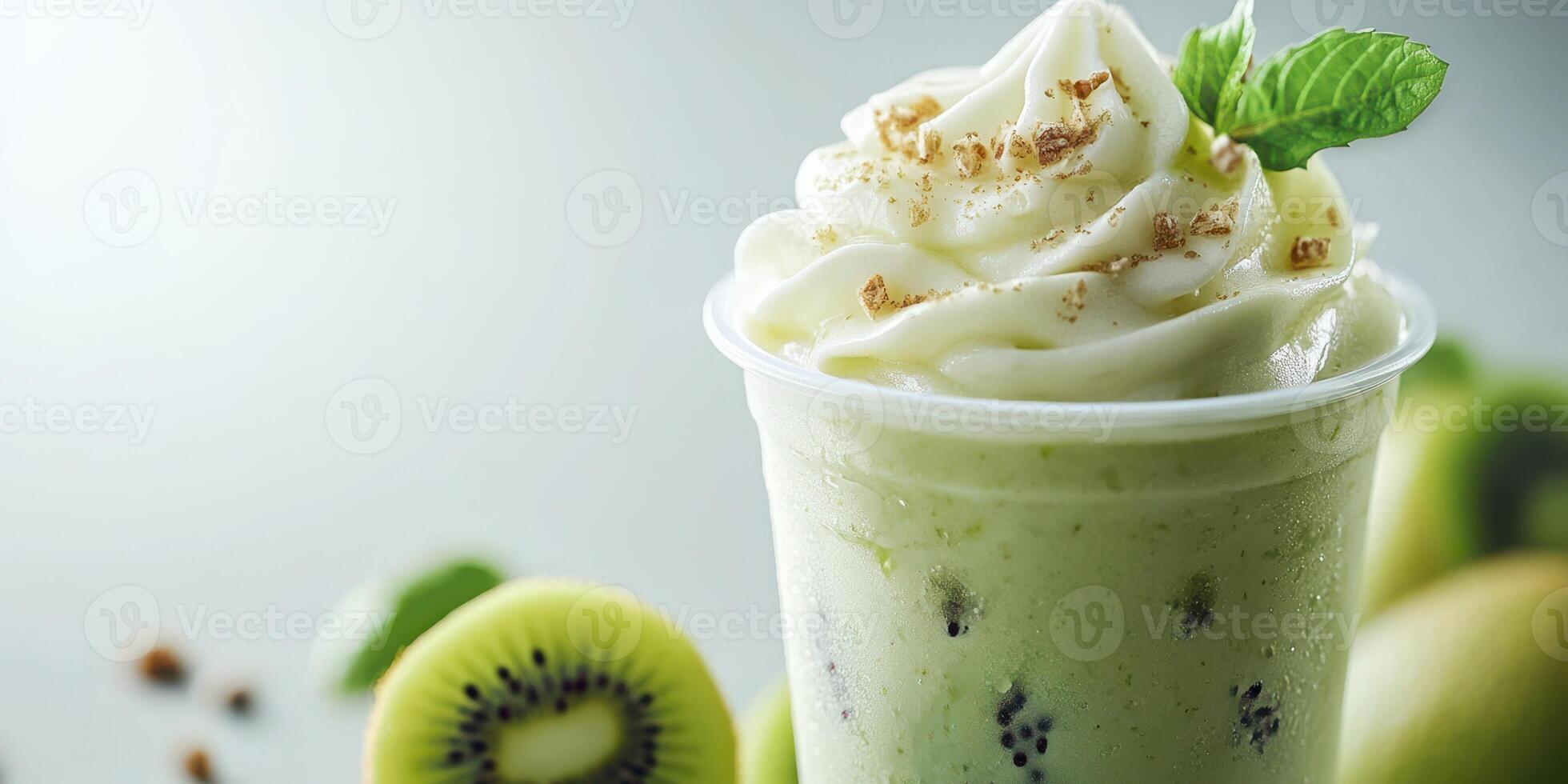 Refreshing kiwi smoothie topped with whipped cream and mint leaves served in a clear cup photo
