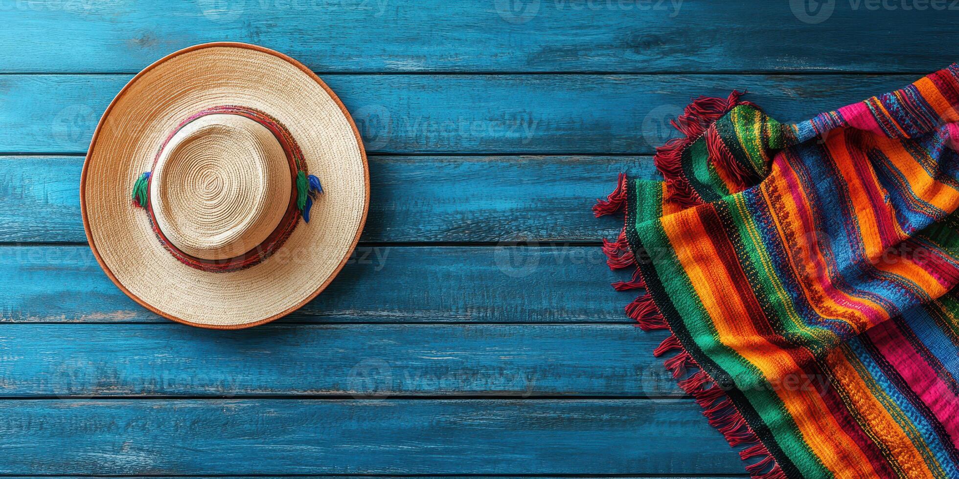 Handmade sombrero resting on a vibrant woven blanket against a blue wooden background photo