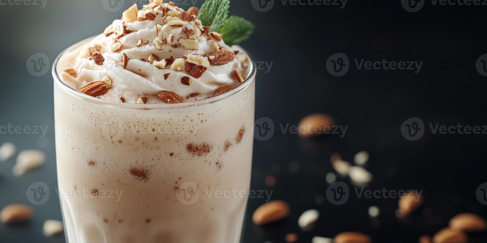 Delicious almond milkshake topped with whipped cream and nuts served in a glass with a mint leaf photo