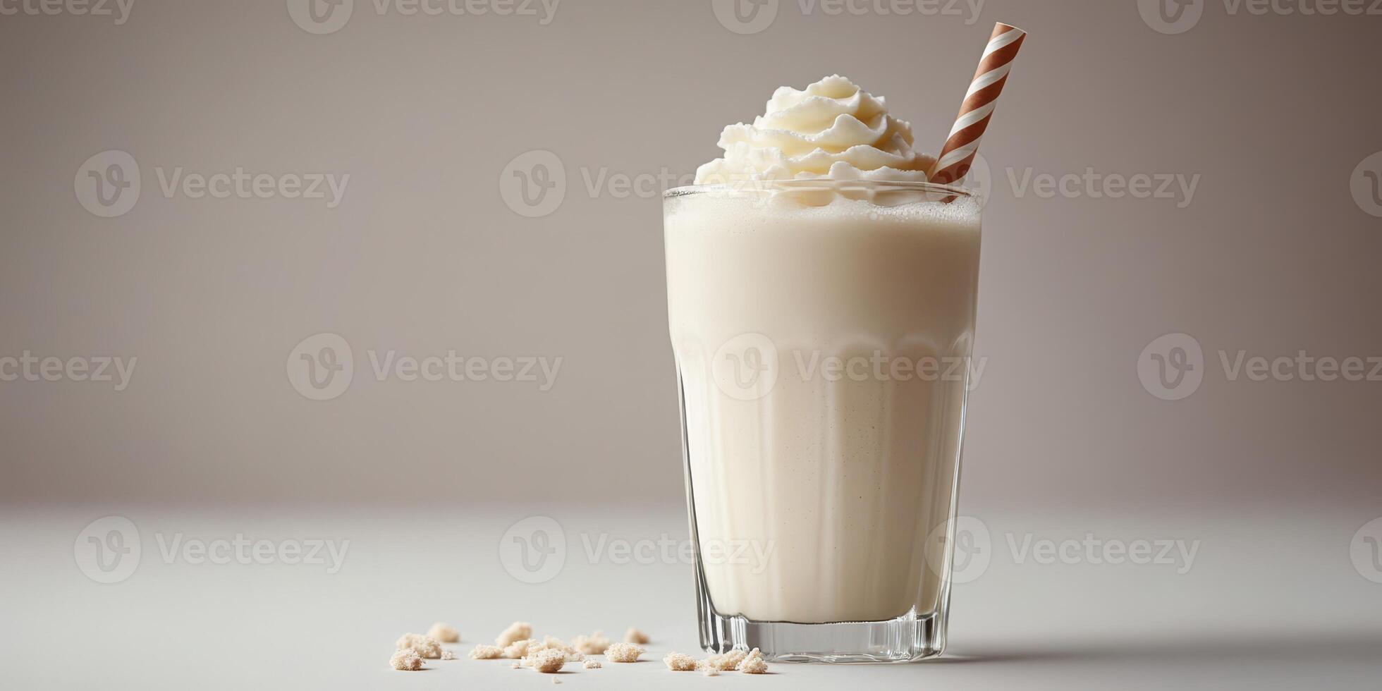 Creamy milkshake served in a glass with whipped topping and a straw on a plain background photo
