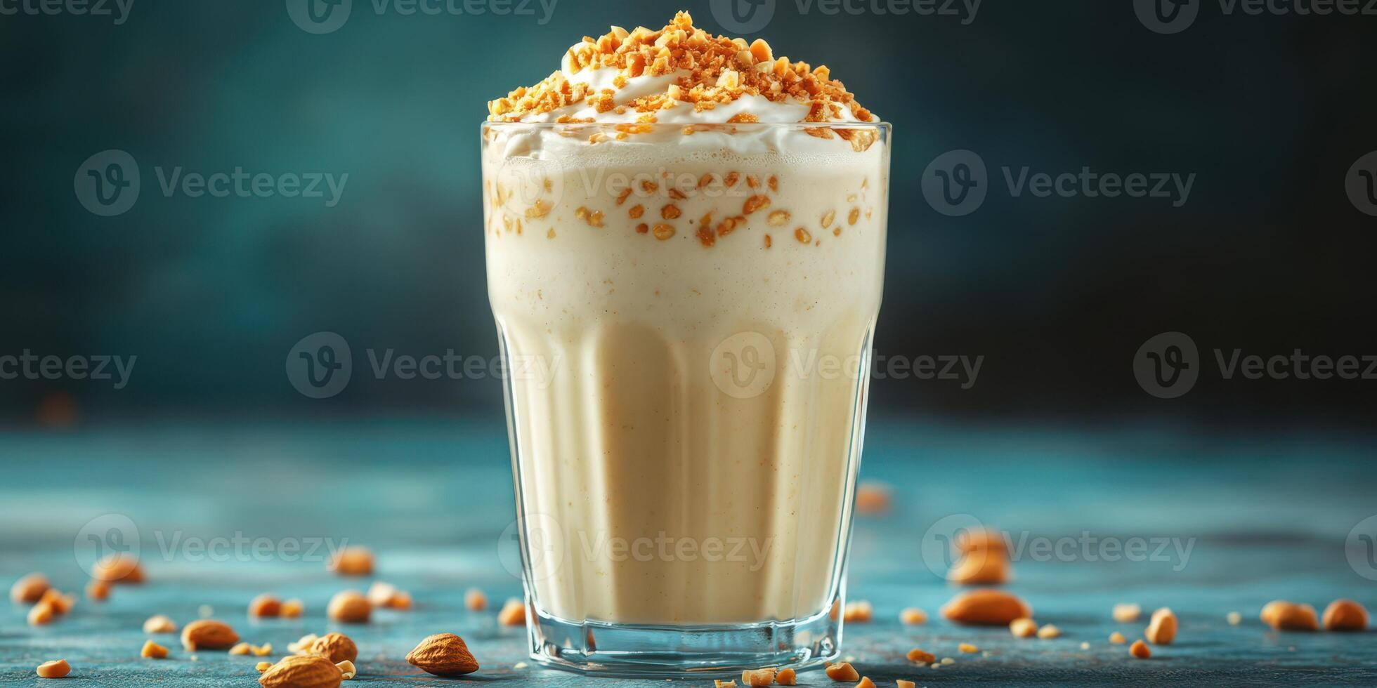 Creamy dessert drink topped with crushed nuts served in a clear glass on a blue background photo