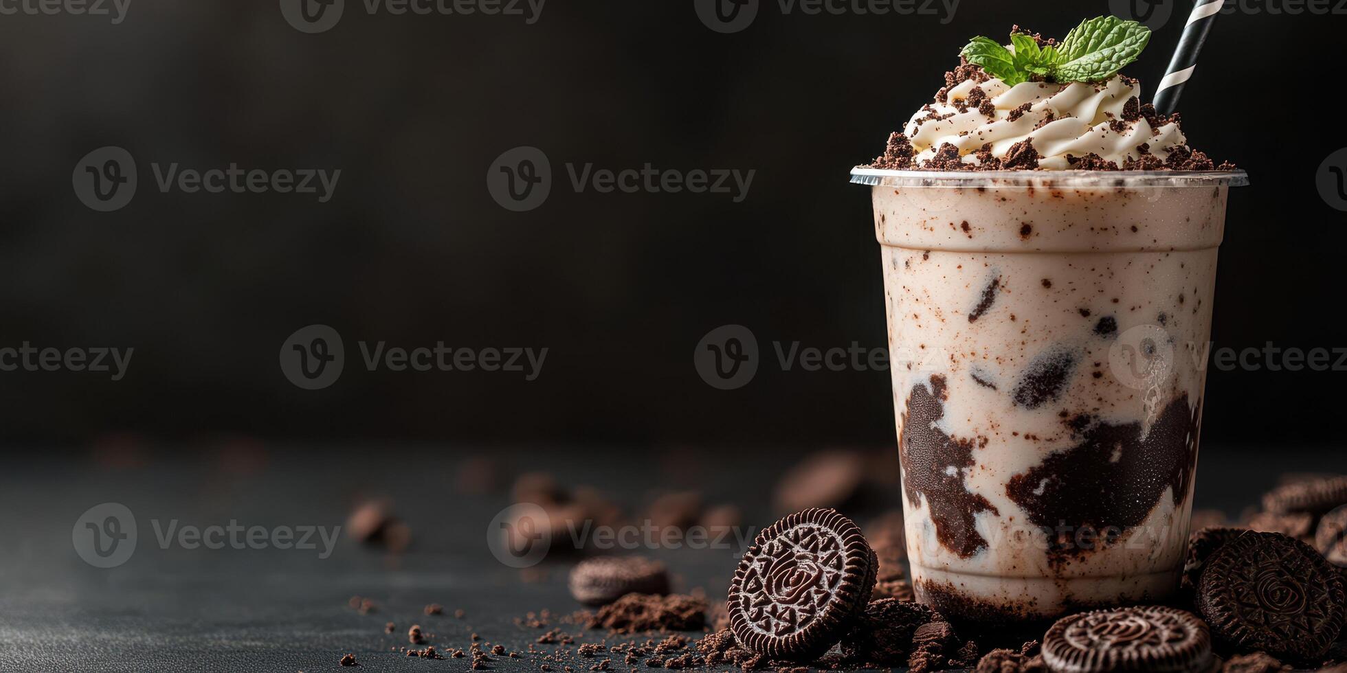Oreo milkshake served in a clear cup with whipped cream and mint on a dark background photo