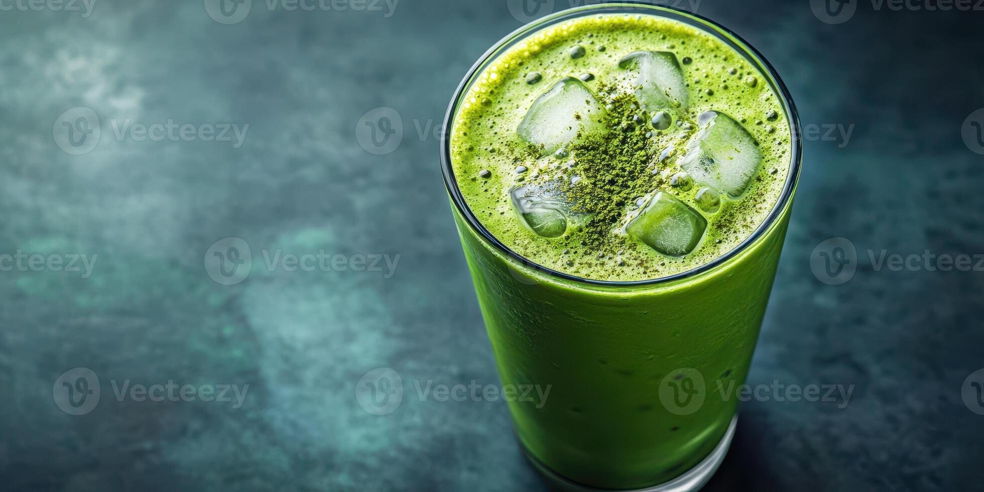 Refreshing green smoothie with ice cubes served in an elegant glass on a dark surface photo