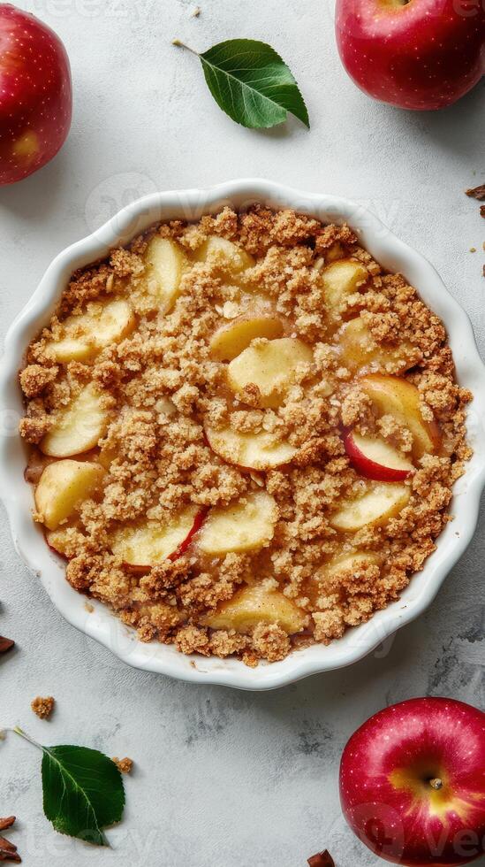 Freshly baked apple crumble dessert with a golden topping and slices of apple on a gray countertop photo