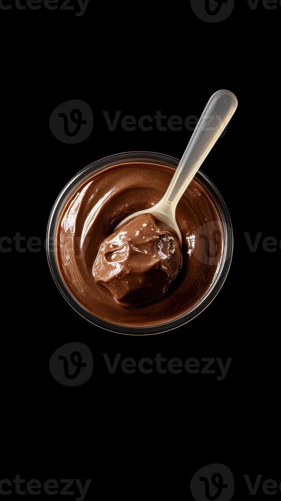 Smooth chocolate dessert in a glass bowl with a spoon on a dark background for indulgent treat lovers photo