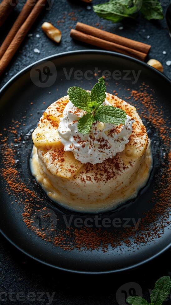 Delightful dessert served in a black dish topped with whipped cream and mint leaves on a dark table photo