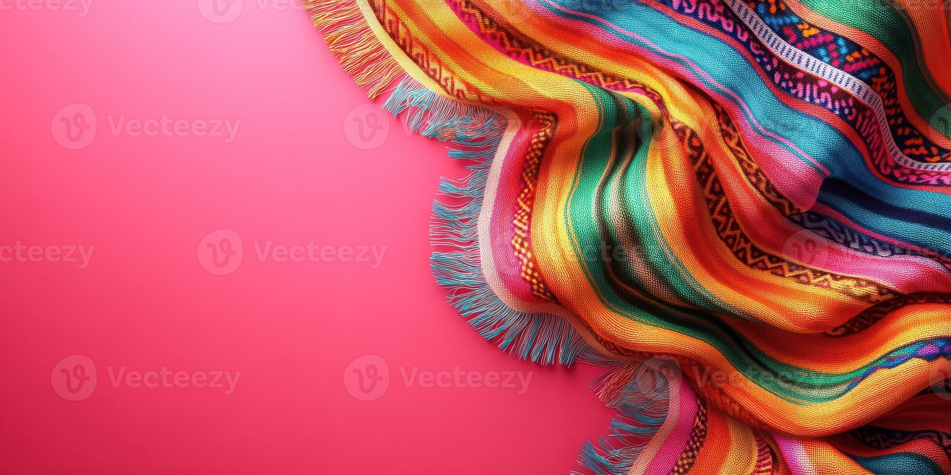 Colorful woven blanket draped on vibrant pink background showcasing intricate patterns and warm hues photo