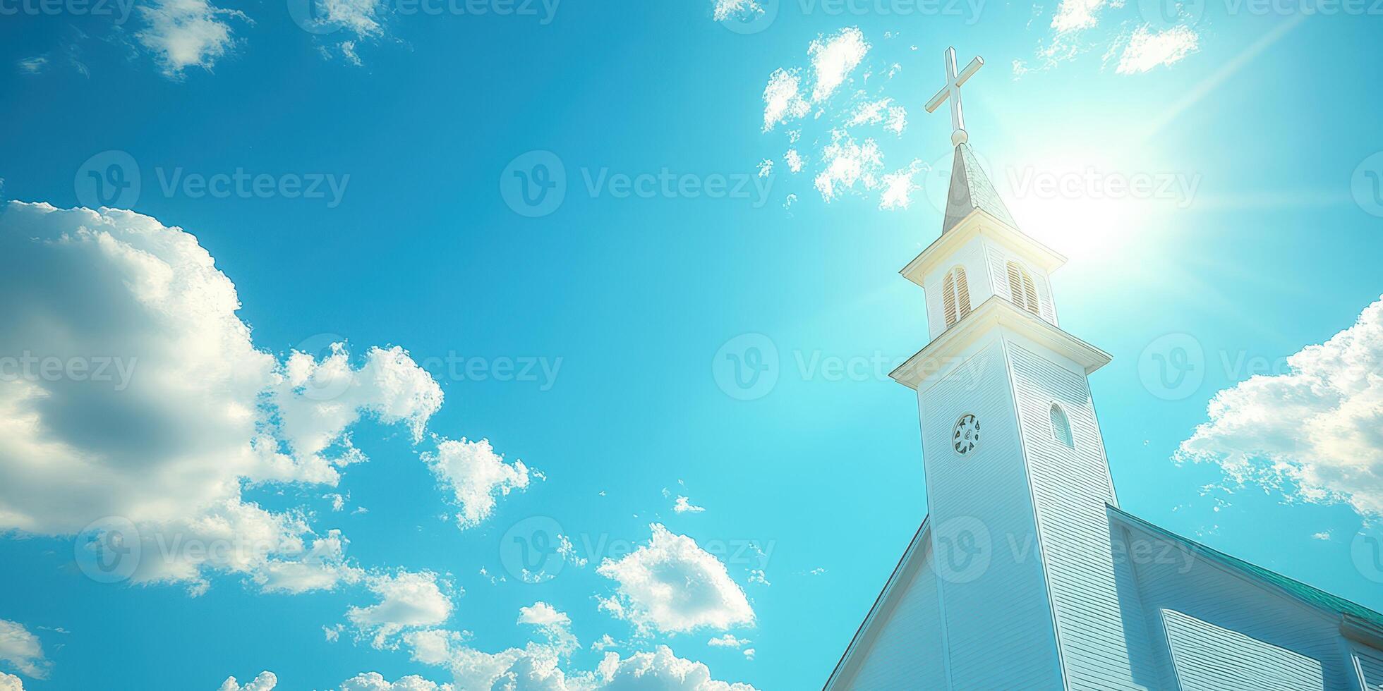Bright sunlight shines over a church steeple against a blue sky with fluffy clouds in a serene daytime setting photo