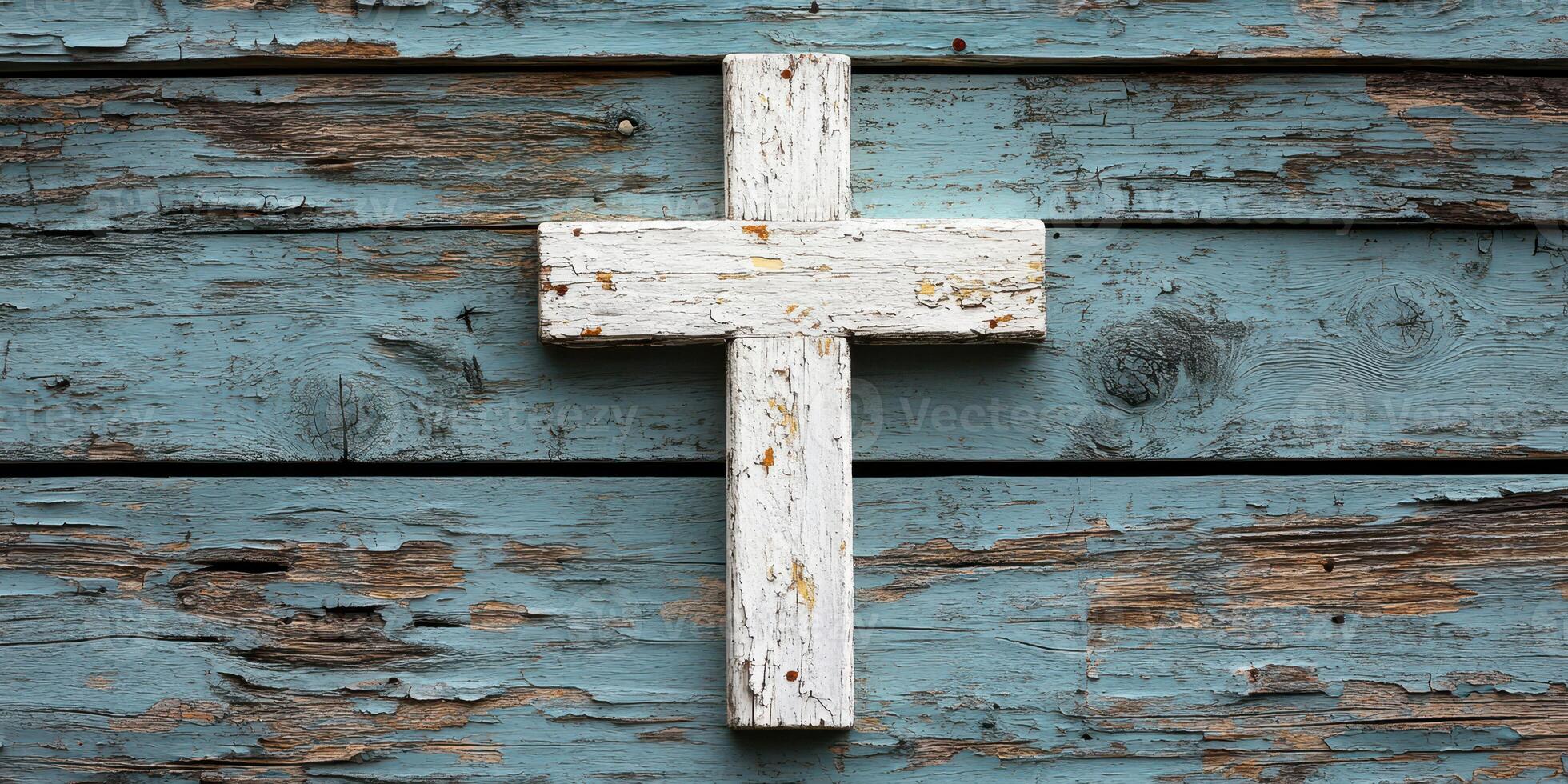 White wooden cross on weathered blue rustic wooden background in a quiet setting suggesting peace and reflection photo