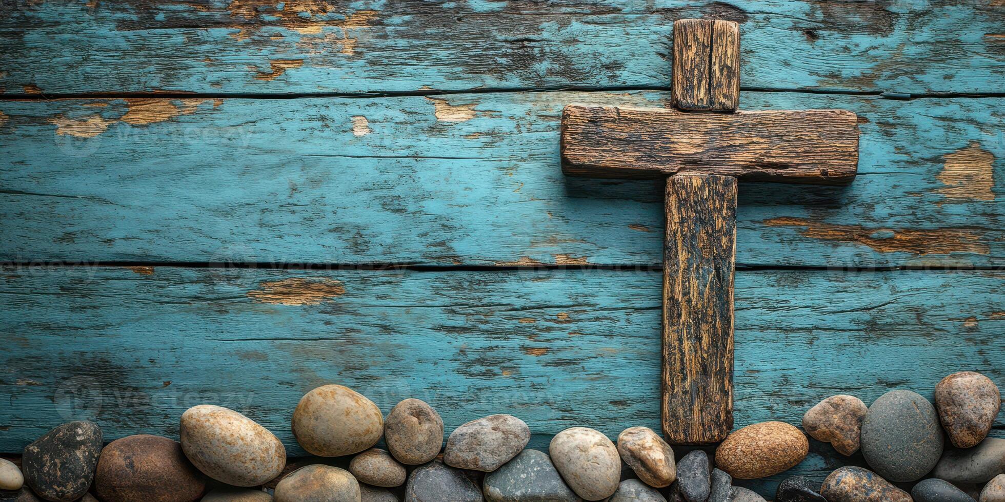 Wooden cross placed on a blue wooden surface surrounded by smooth stones creates a tranquil setting photo
