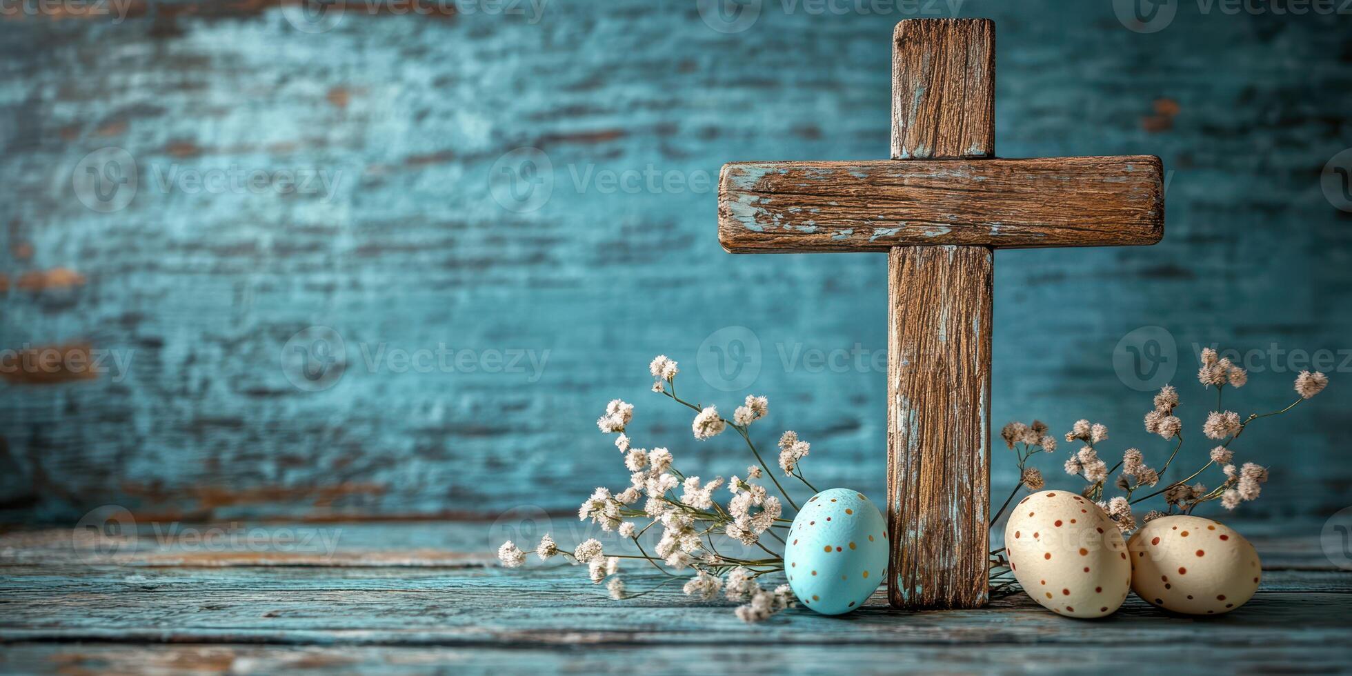 Rustic wooden cross with decorated eggs and dried flowers on a weathered blue background photo