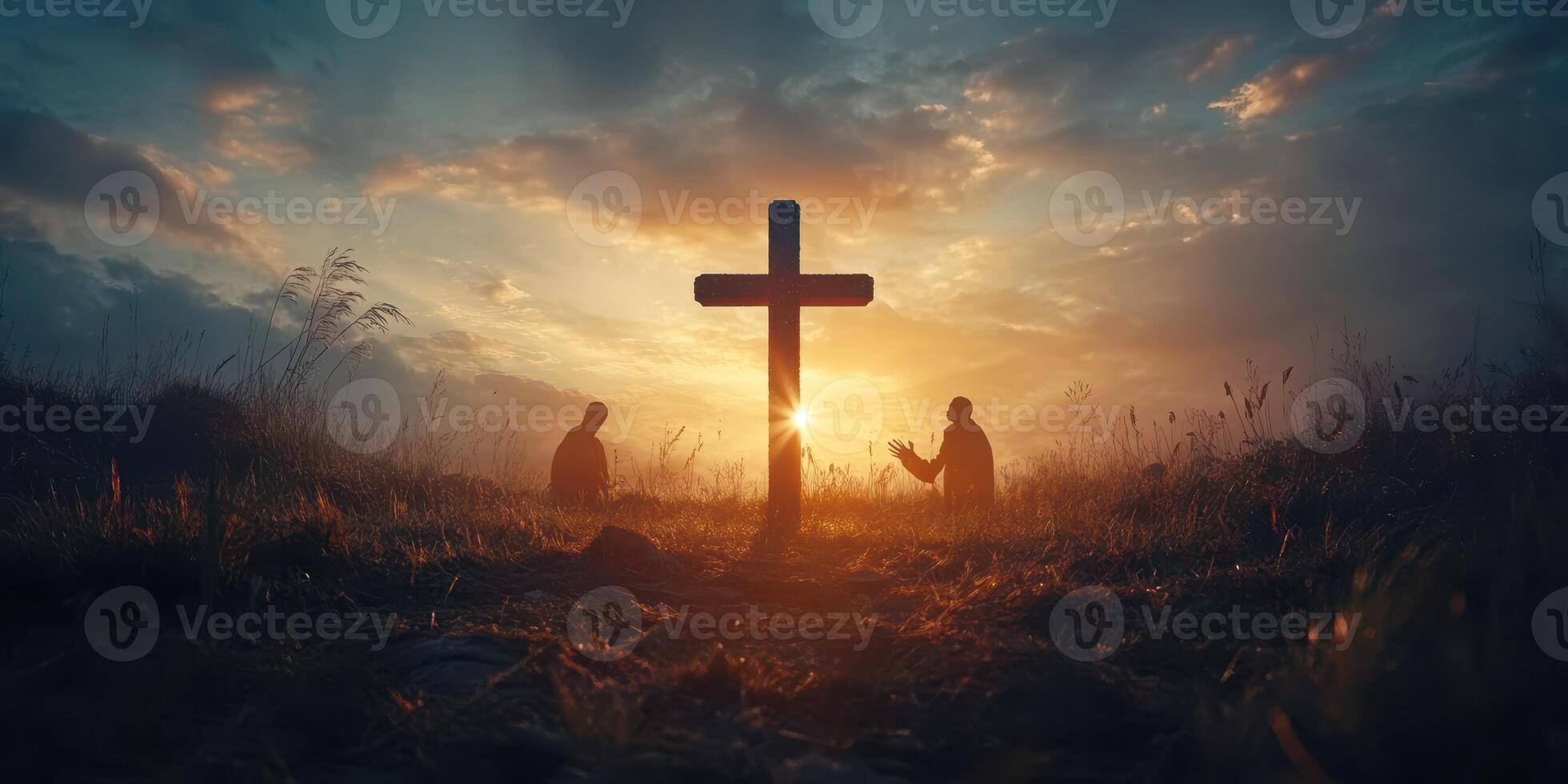 Two individuals in prayer at sunset beside a cross in a tranquil field photo