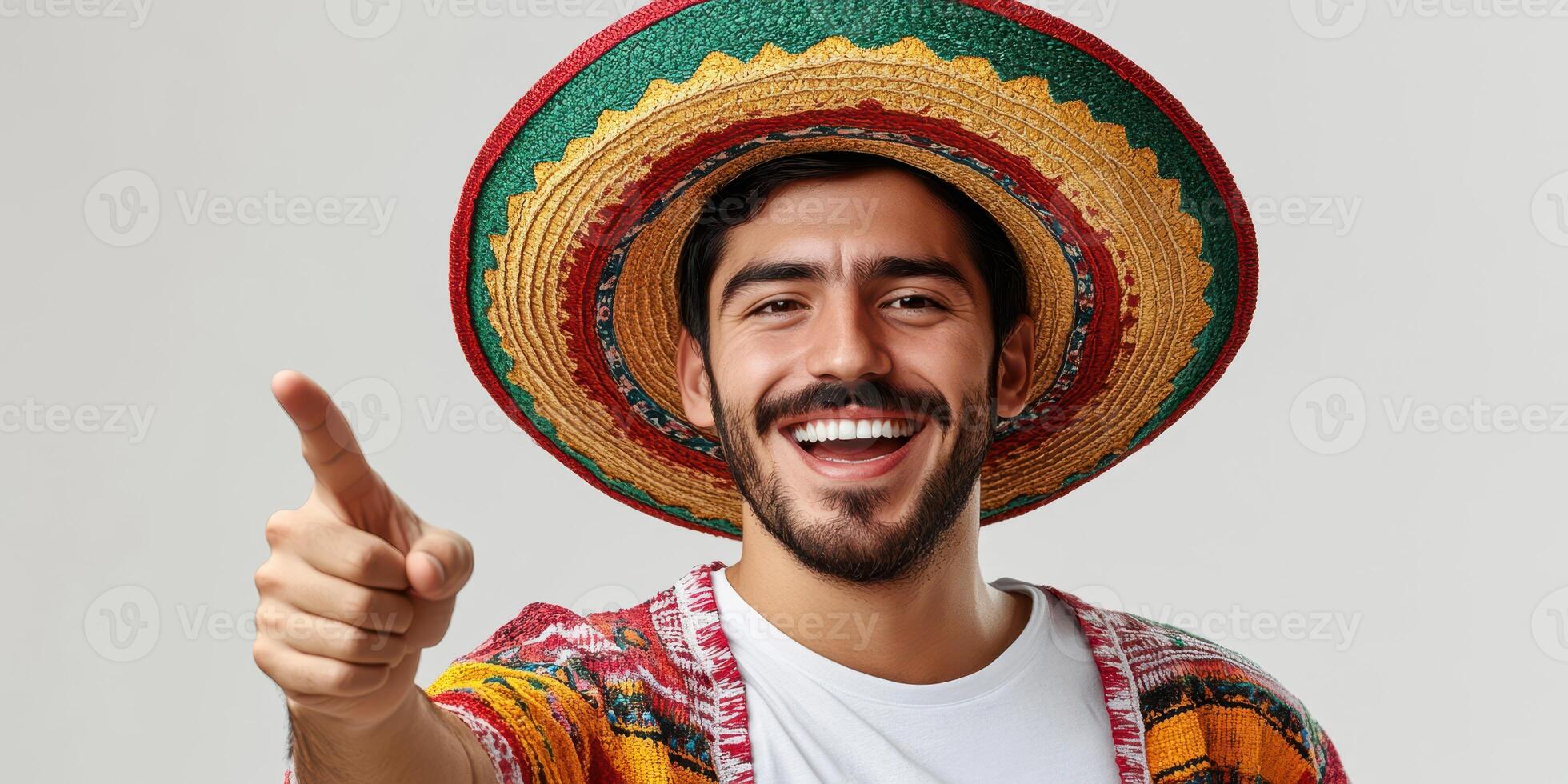 Young man in colorful hat smiling widely and pointing joyfully at the camera during a festive celebration in a studio setting photo