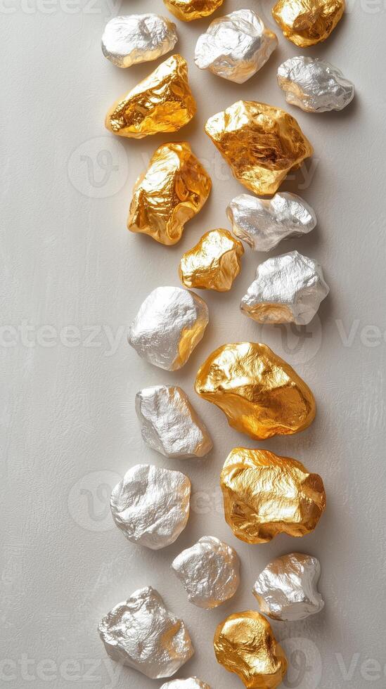 Gold and silver foil rocks arranged in a stylish pattern on a neutral background photo