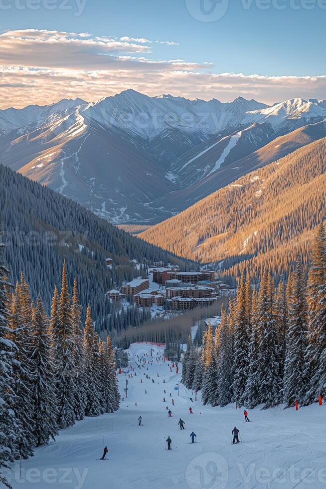 Skiers on a snowy mountain slope overlooking a resort with surrounding peaks photo