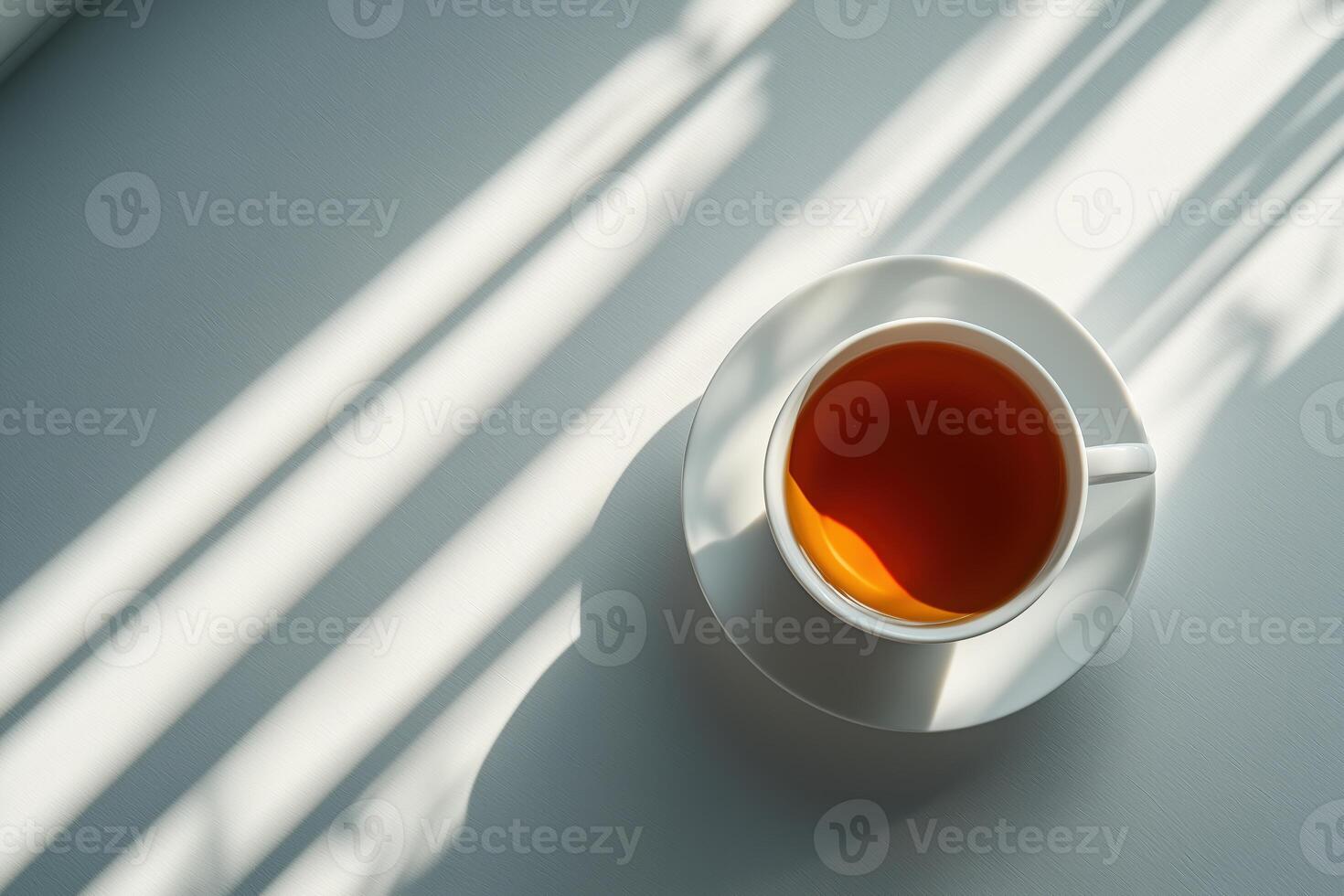 Close-up of a white cup filled with orange tea on a light background with shadow patterns photo