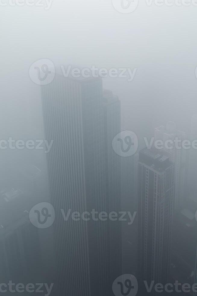 Tall skyscrapers shrouded in thick fog creating a mysterious urban atmosphere photo