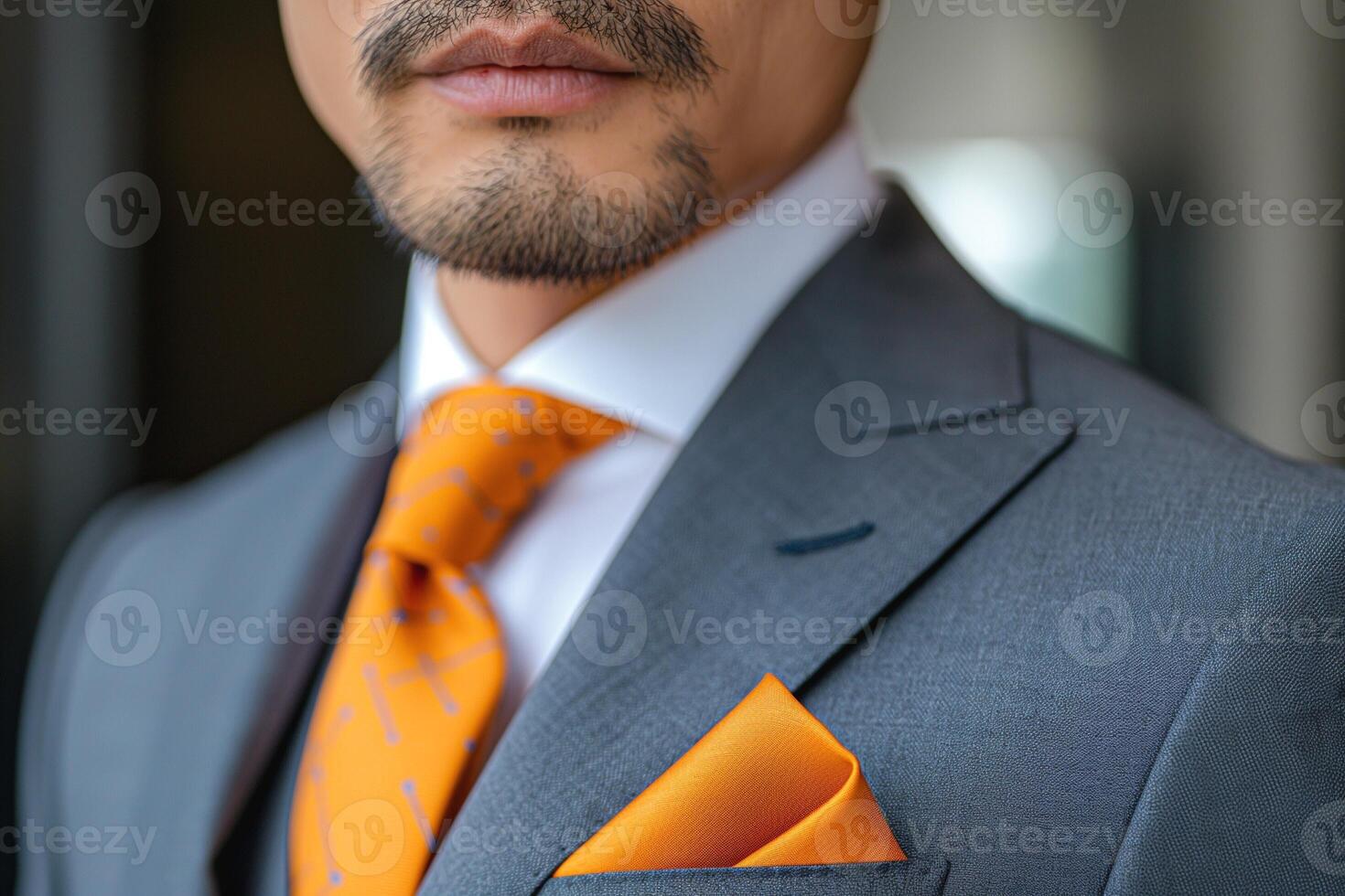 Close-up of a well-dressed Asian man in a tailored suit, featuring a vibrant orange tie and pocket square, exuding sophistication. photo
