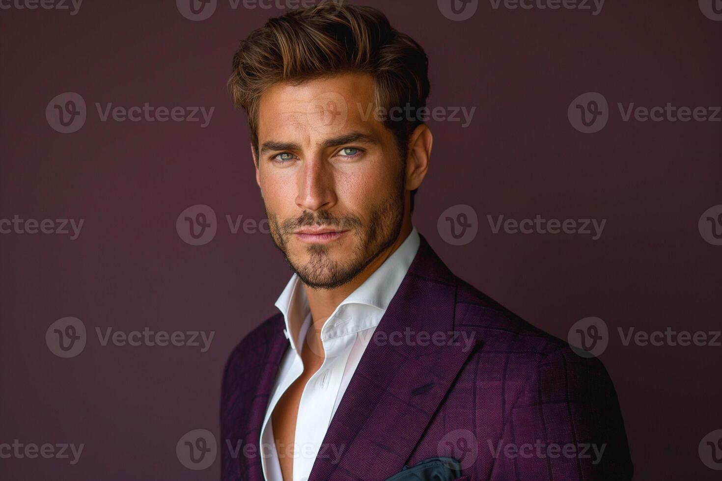 Stylish Caucasian man with blue eyes poses confidently in a rich purple suit against a deep background. photo
